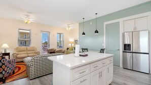 Una cocina moderna con muebles blancos, un refrigerador de acero inoxidable y una isla central.