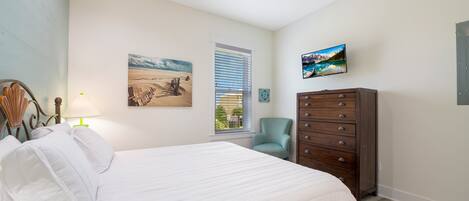 A bedroom with a bed, a dresser, a chair, a window with blinds, and wall art.