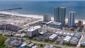 Un hotel costero con varios edificios altos, una playa y un muelle.