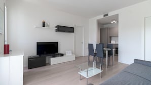 Una sala de estar moderna con un televisor de pantalla plana, una mesa de centro de vidrio y un sofá gris.
