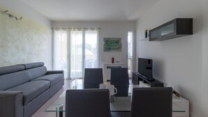 Una sala de estar moderna con un sofá gris, una mesa de centro de vidrio y un televisor sobre un mueble.