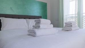 Una cama bien hecha con sábanas blancas y cabecera gris.