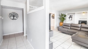 A modern living room with a sectional sofa, a flat-screen TV, and a decorative tree artwork on the wall. -  POOL, Sleeps 10, CENTRALY LOCATED, game room, pets. great for LONG TERM stays. (El Paso)
