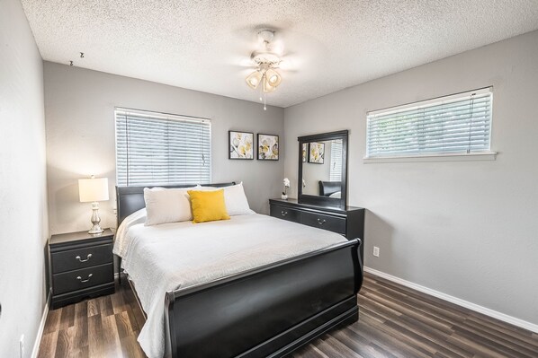 A bedroom with a bed, nightstands, a dresser, a ceiling fan, and two windows with blinds. - POOL, Sleeps 10, CENTRALY LOCATED, game room, pets. great for LONG TERM stays. (El Paso)