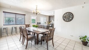 A dining area with a wooden table and chairs, a chandelier, and a clock on the wall. -  POOL, Sleeps 10, CENTRALY LOCATED, game room, pets. great for LONG TERM stays. (El Paso)