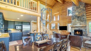 Un intérieur spacieux de chalet en bois, comprenant un coin repas, une cuisine et un salon.