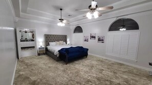 Ein Schlafzimmer mit einem großen Bett, zwei Deckenventilatoren und einem Kleiderschrank.