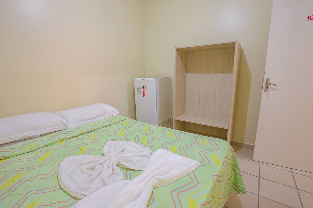 A hotel room with a bed, a wardrobe, and a refrigerator.