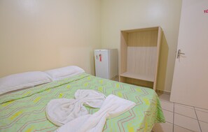 Quarto de hotel com cama, guarda-roupa e frigorífico.