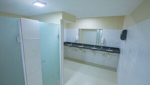 A public restroom with a glass partition, a sink, and a mirror. - Pousada Estrela Azul (João Pessoa)