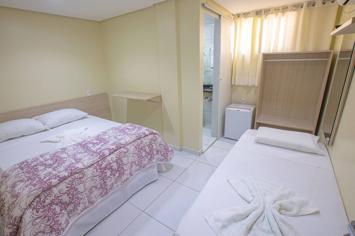 A hotel room with two beds, a bathroom, and a shower area.