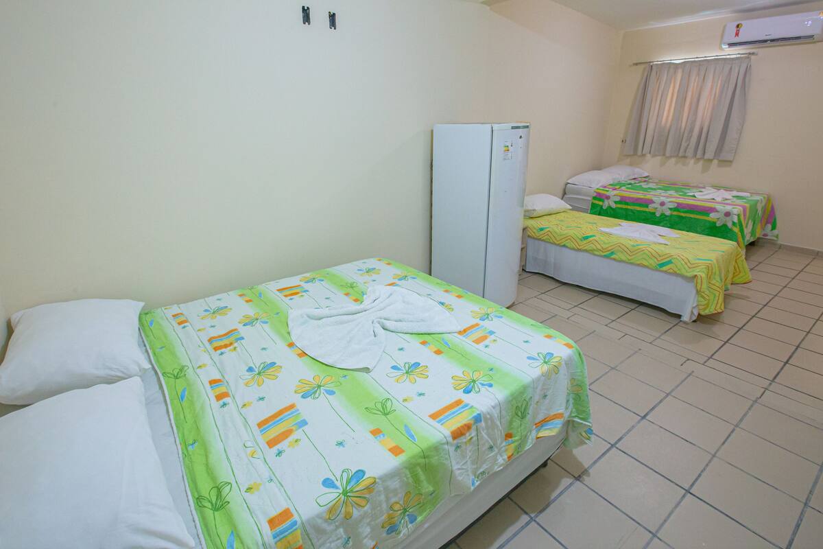 A room with two single beds, a wardrobe, and an air conditioner on the wall.