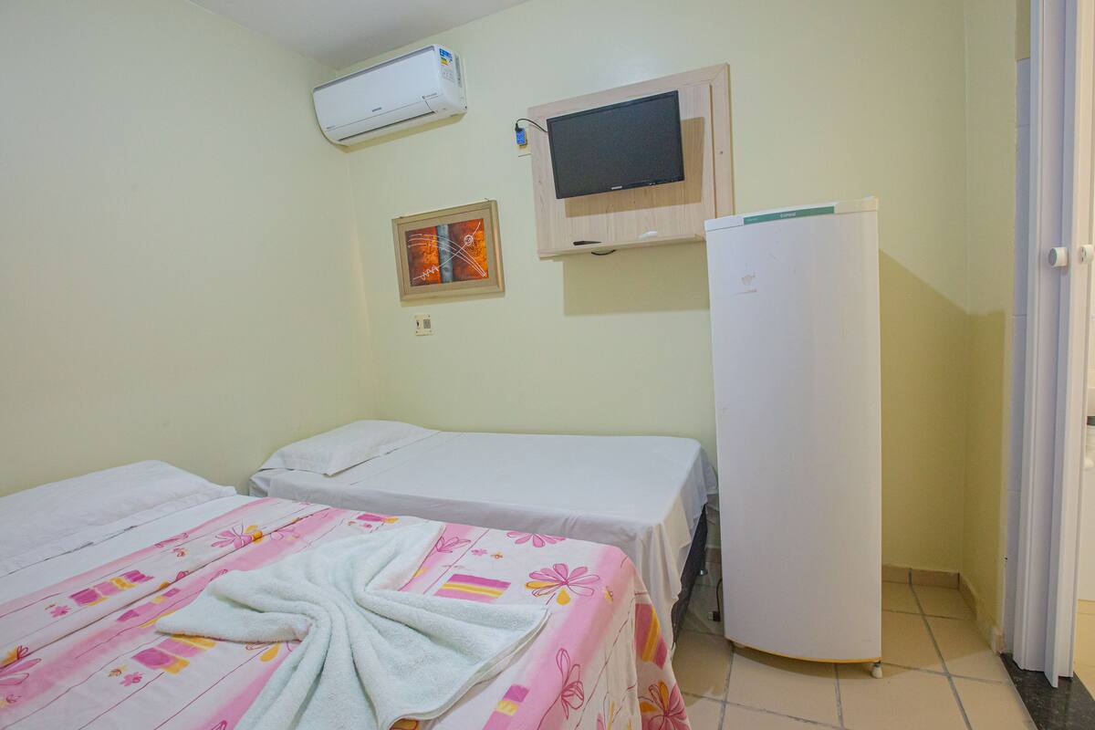 A hotel room with two beds, a television, and a refrigerator.