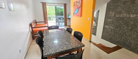A dining area with a granite table, black chairs, and a view of the outdoors through a glass door.