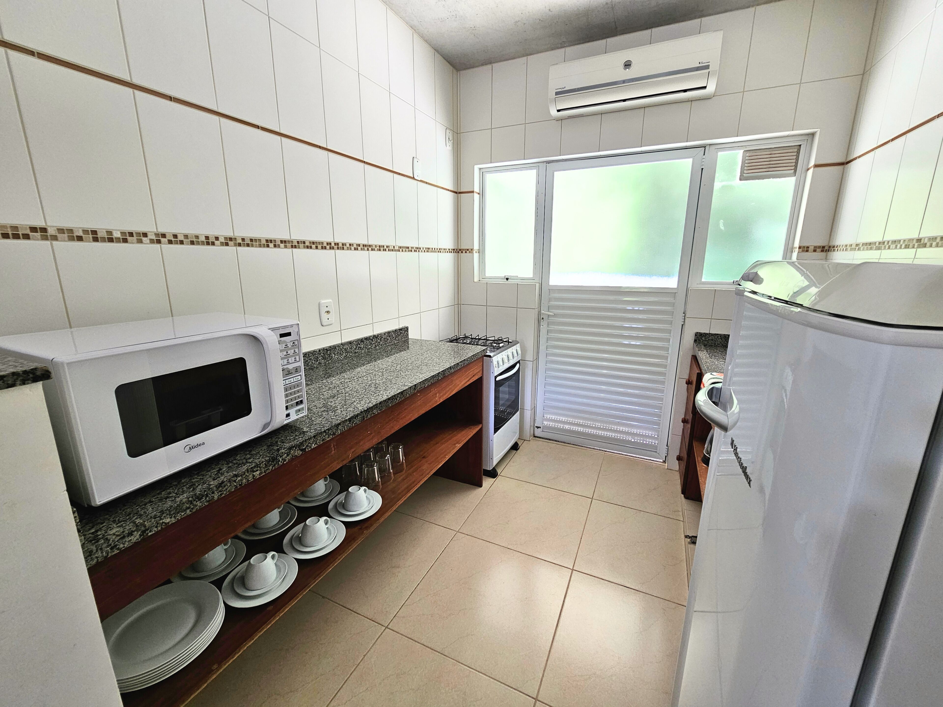 A compact kitchen with white cabinets, a microwave, a stove, and a refrigerator.