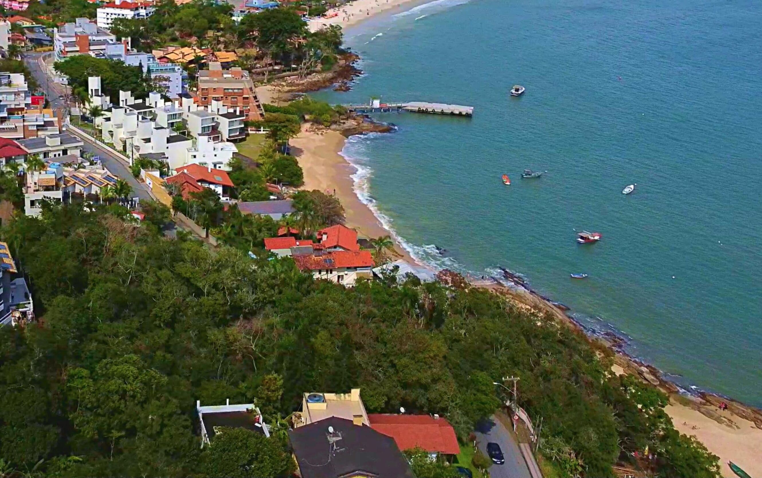 Une vue aérienne d’une zone côtière avec des bâtiments, une plage et des bateaux.