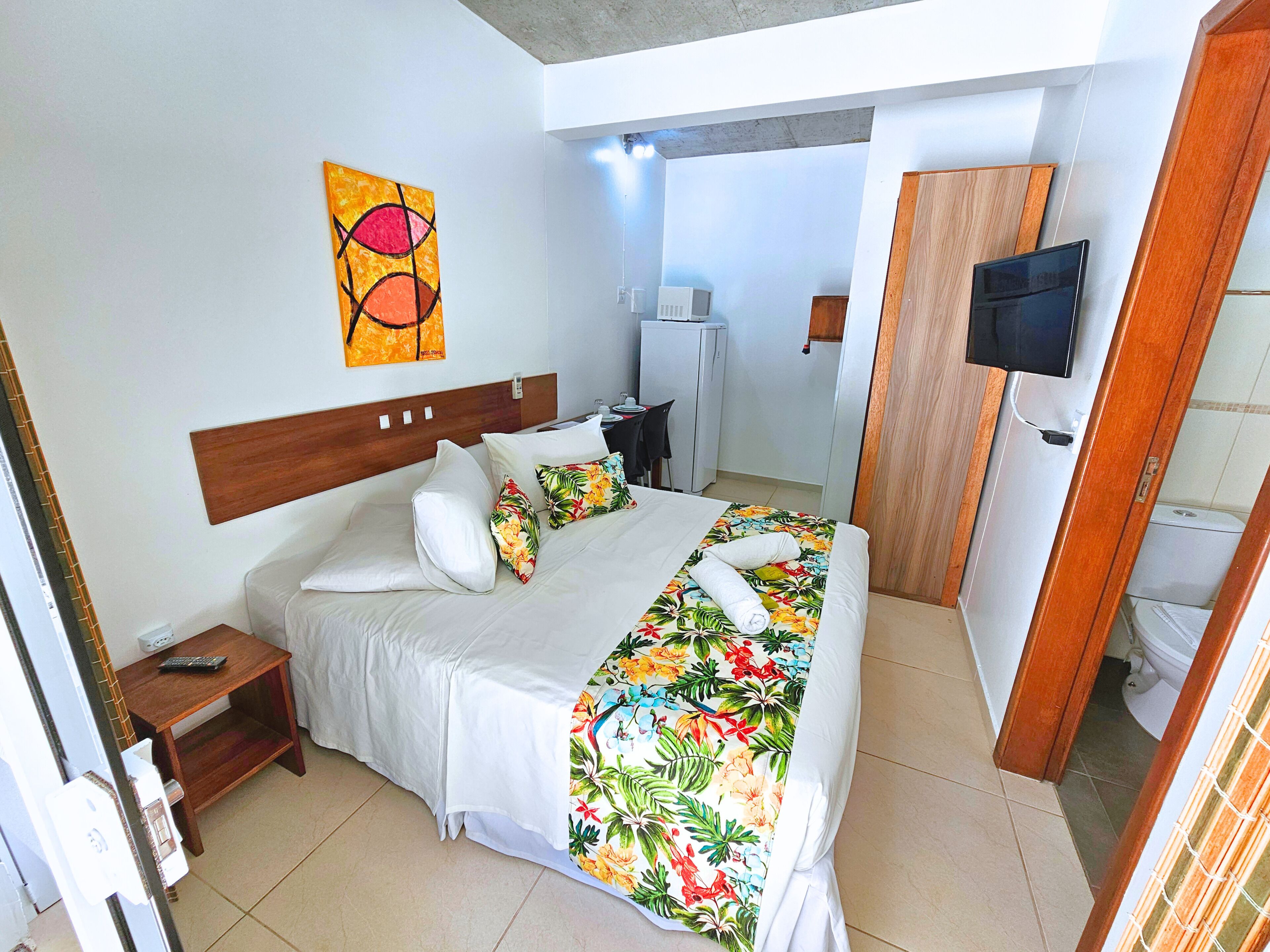 Ein Hotelzimmer mit Bett, Fernseher, Schreibtisch mit Stuhl und angrenzendem Badezimmer.