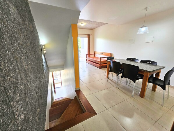 A modern interior with a dining area, a staircase, and a view of the outdoors.