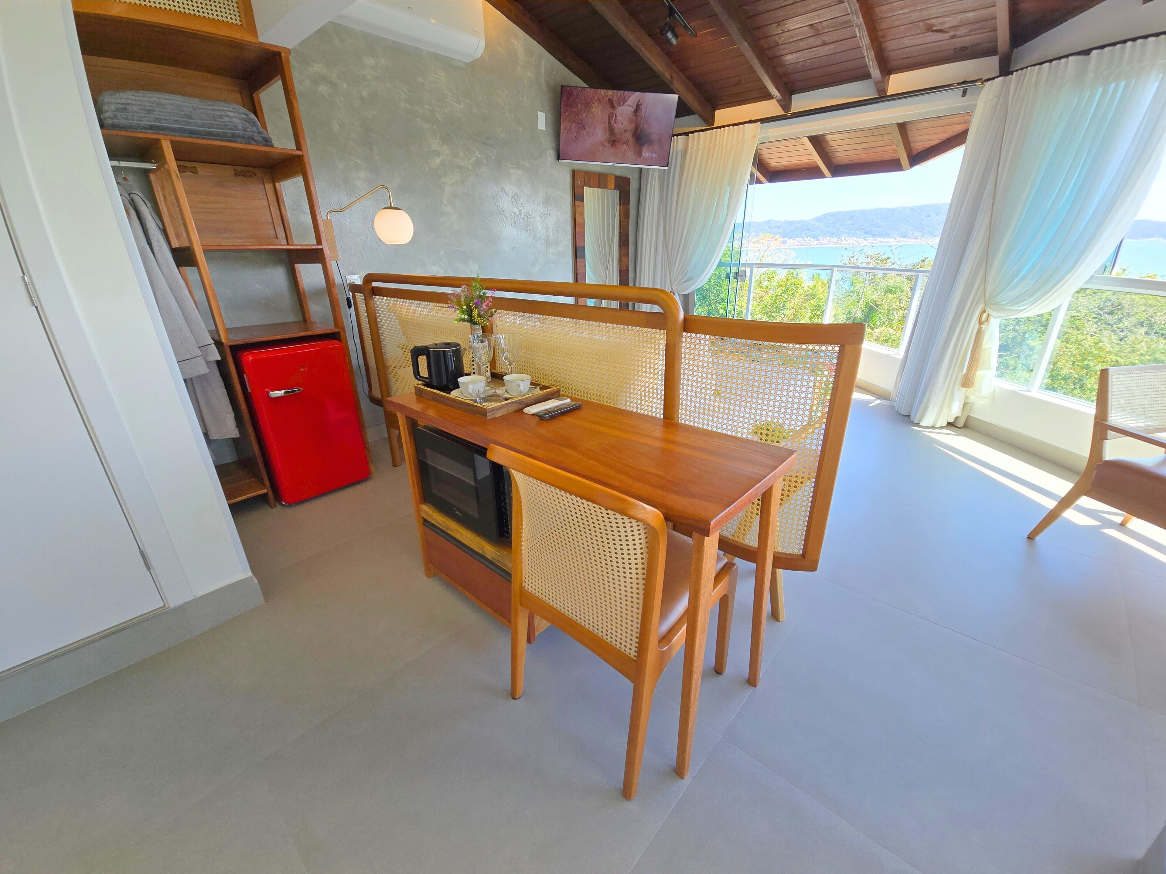 A compact kitchen with a wooden table, a red fridge, and a TV mounted on the wall.
