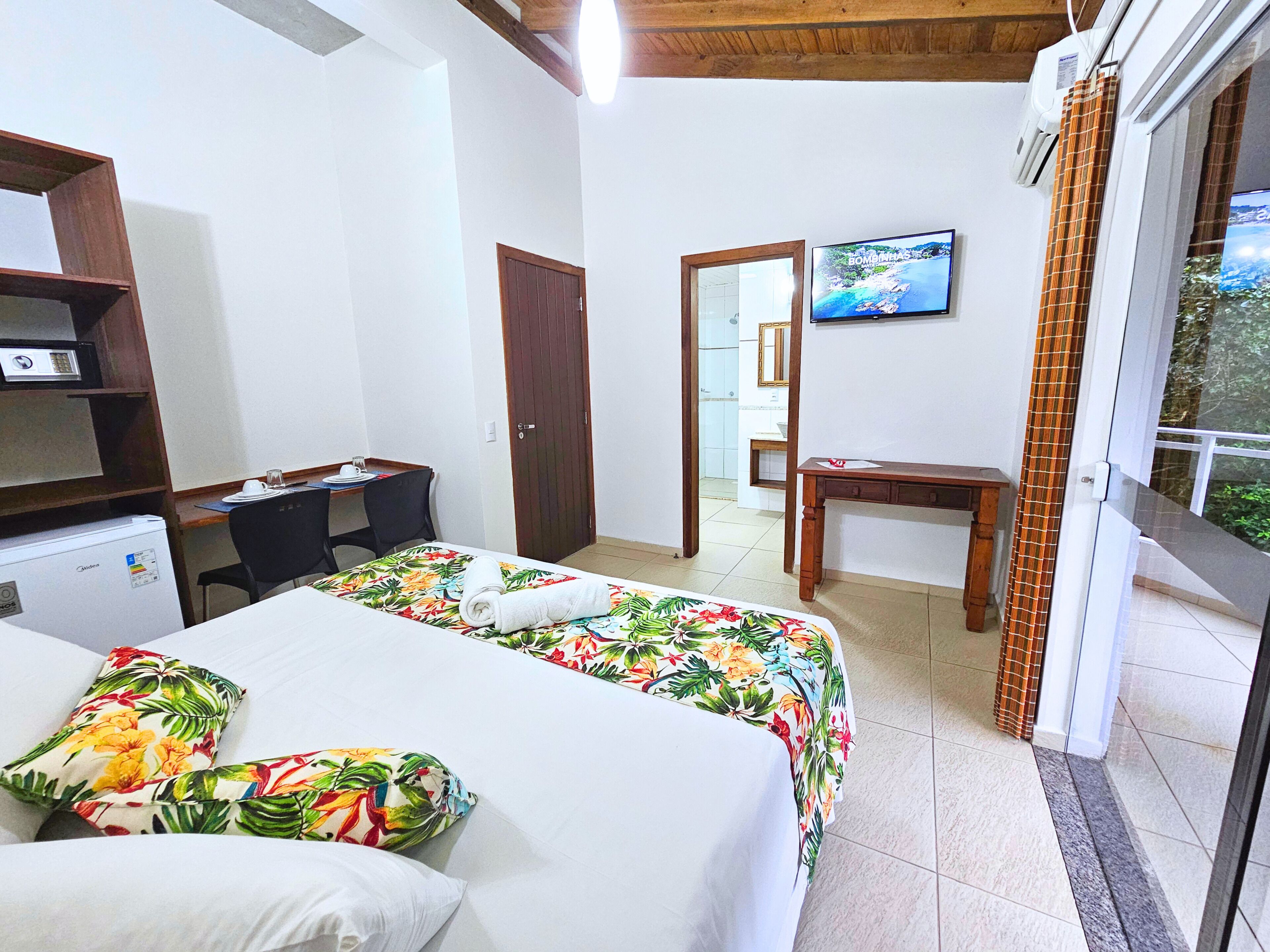 Une chambre d’hôtel avec un lit, un bureau, une télévision et une fenêtre donnant sur un paysage agréable.