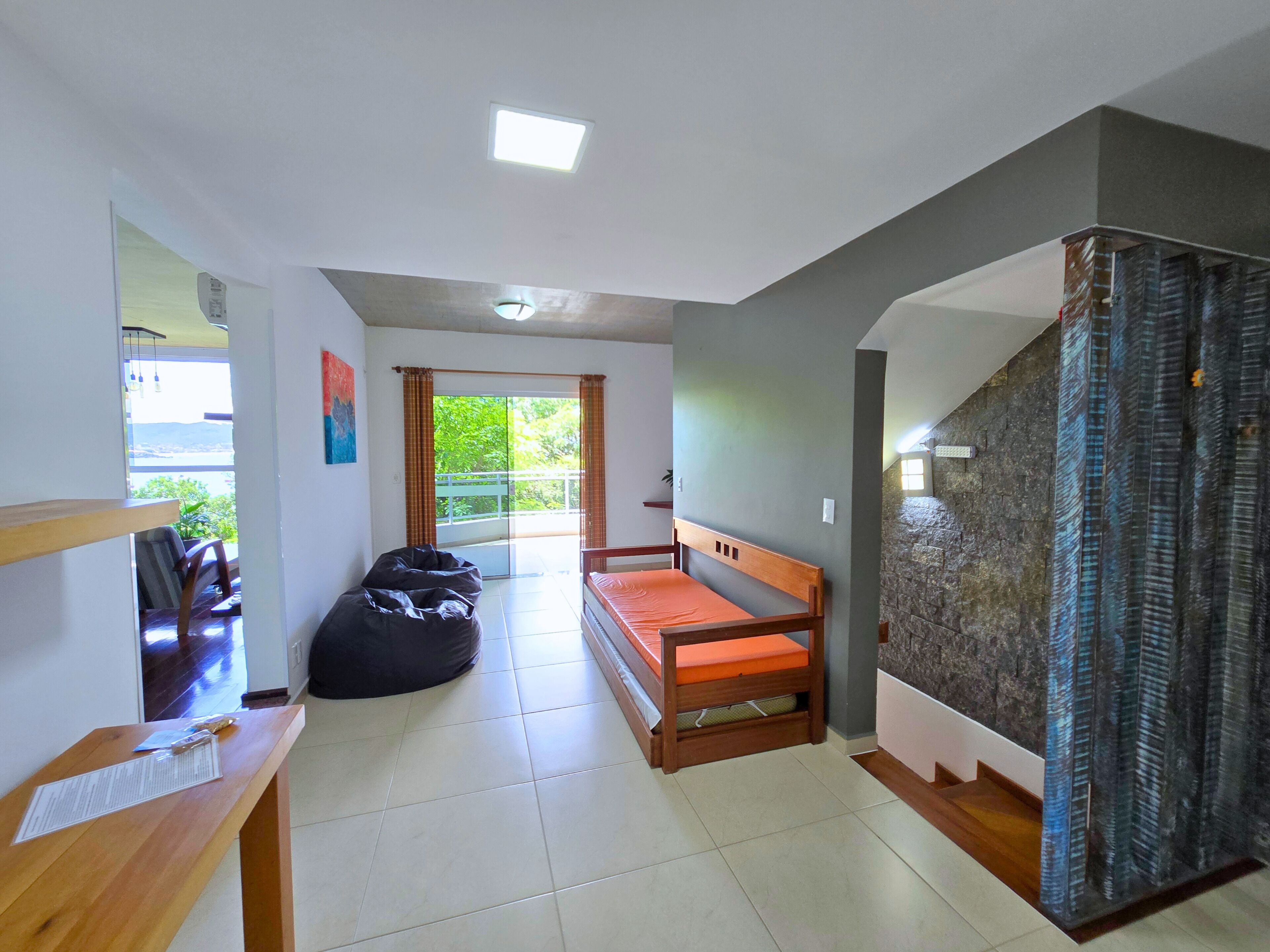 A room with a bed, a desk, a chair, and a view of greenery outside.