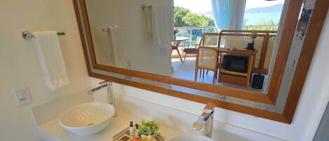 A bathroom with two sinks, a large mirror, and a view of a balcony with outdoor furniture.