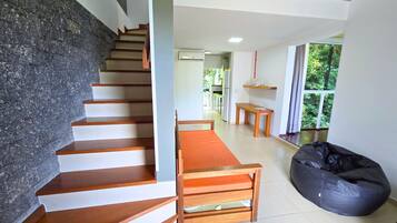 Un interior moderno con una escalera, un sillón de peluche y vistas al exterior.