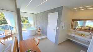 Un baño moderno con bañera, ducha y tocador con un espejo grande.