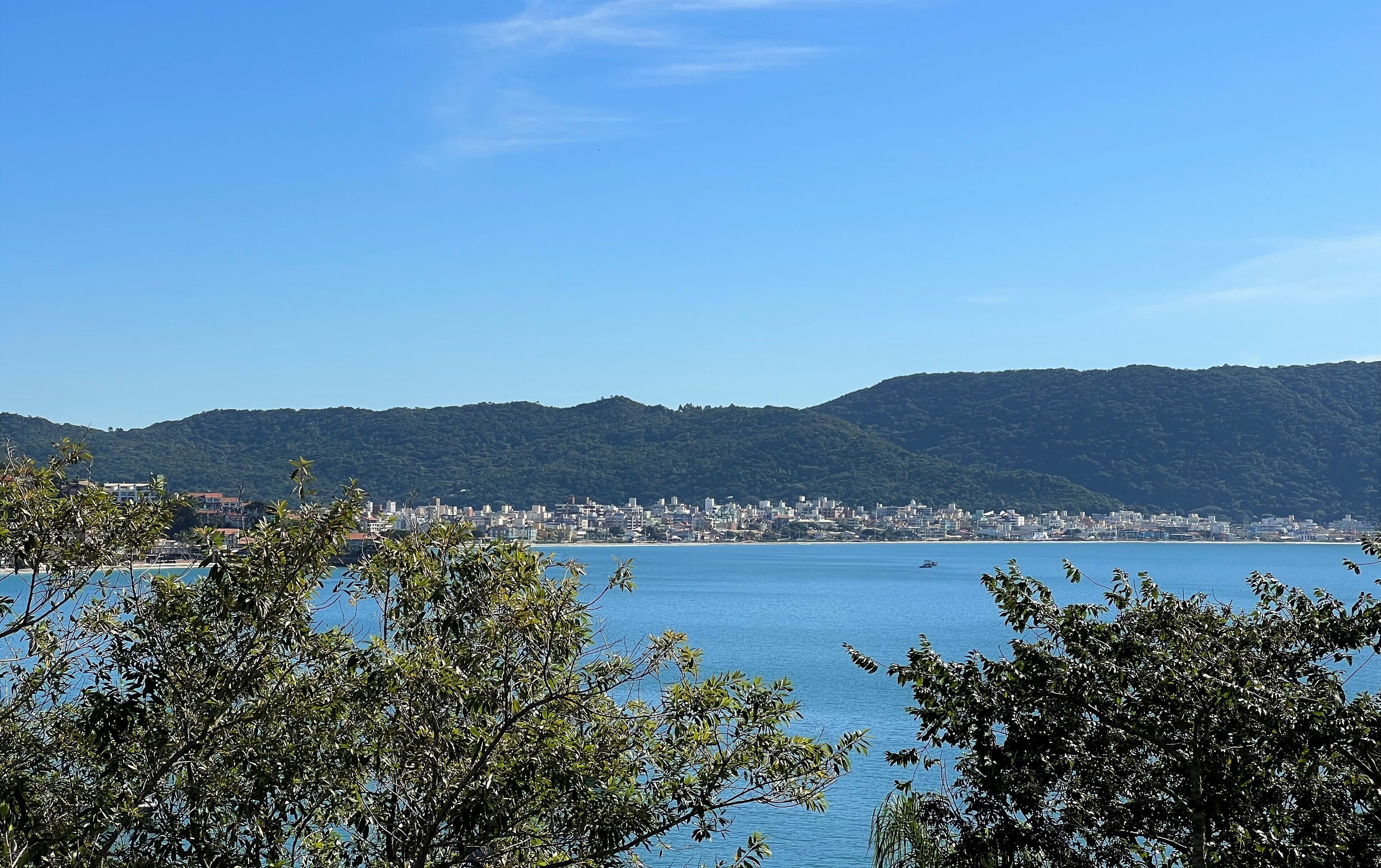 Un paisaje urbano costero con vista al mar y montañas al fondo.