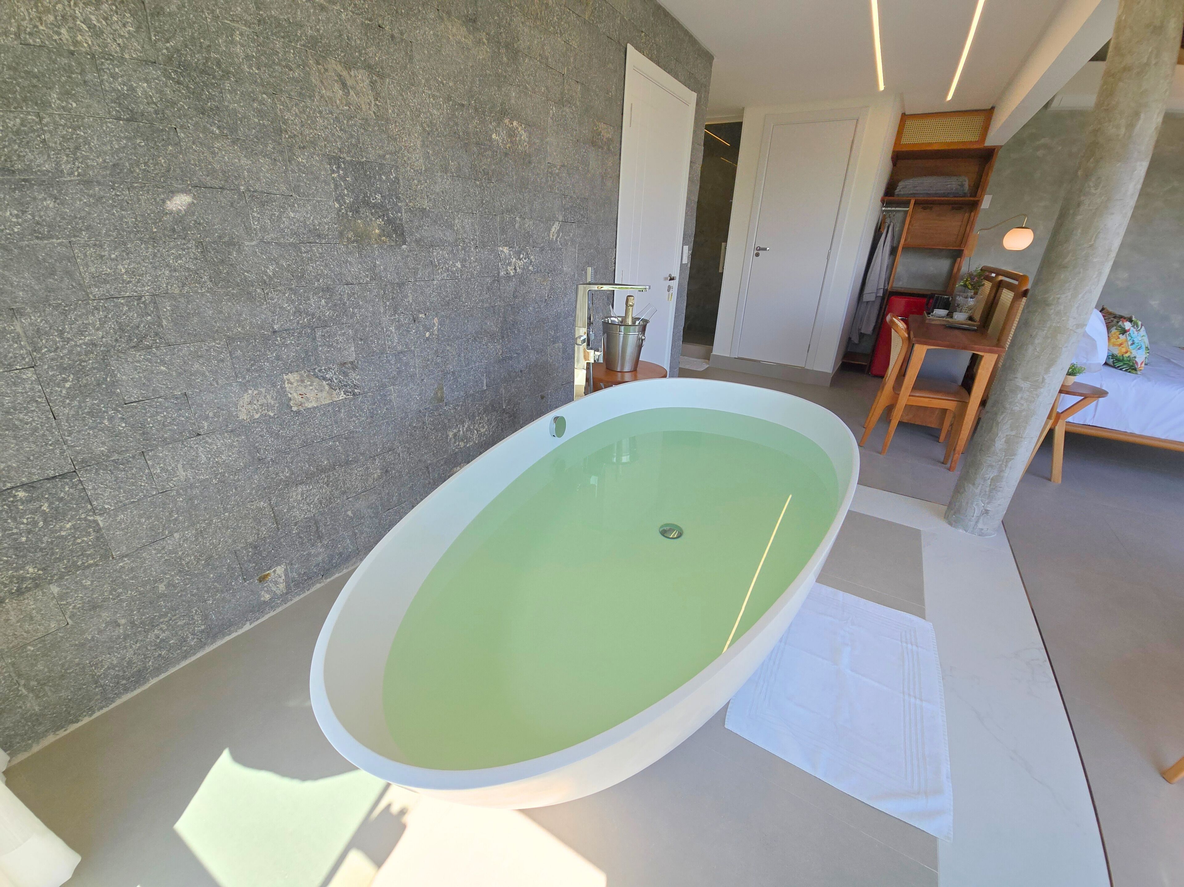 Ein modernes Badezimmer mit einer freistehenden Badewanne, einer Steinwand und einem hölzernen Waschtisch.