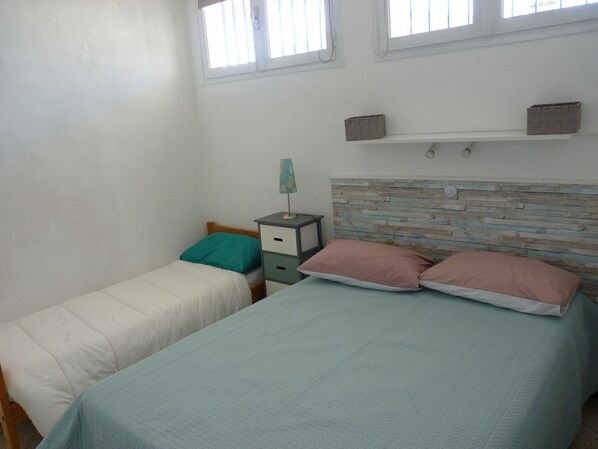 A bedroom with two beds, a nightstand, a dresser, and a window. - Sol-y-Days Hespérides, Family apartment 50m from the beach (Le Grau-du-Roi)