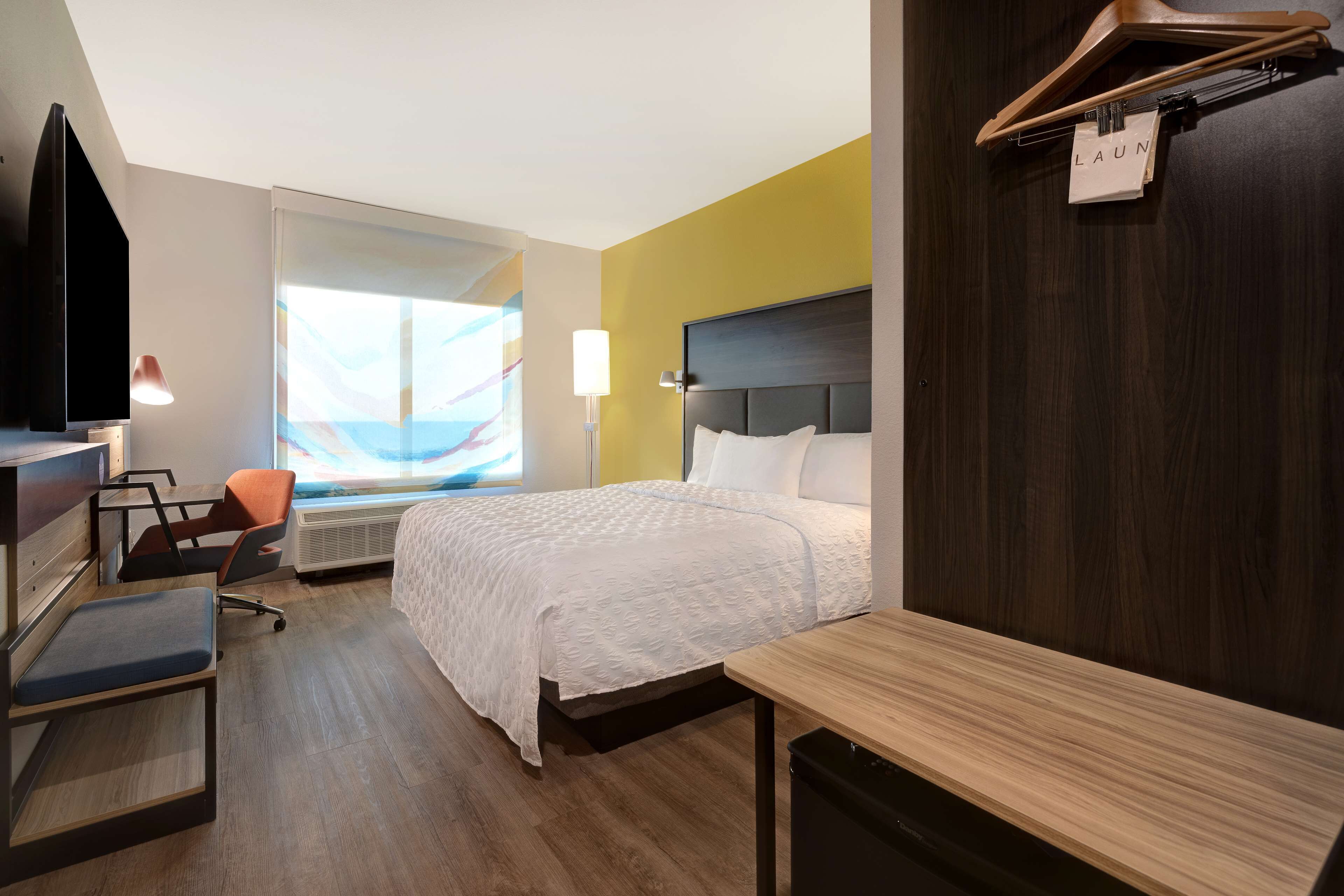 Een hotelkamer met een bed, bureau, stoel en een televisie.
