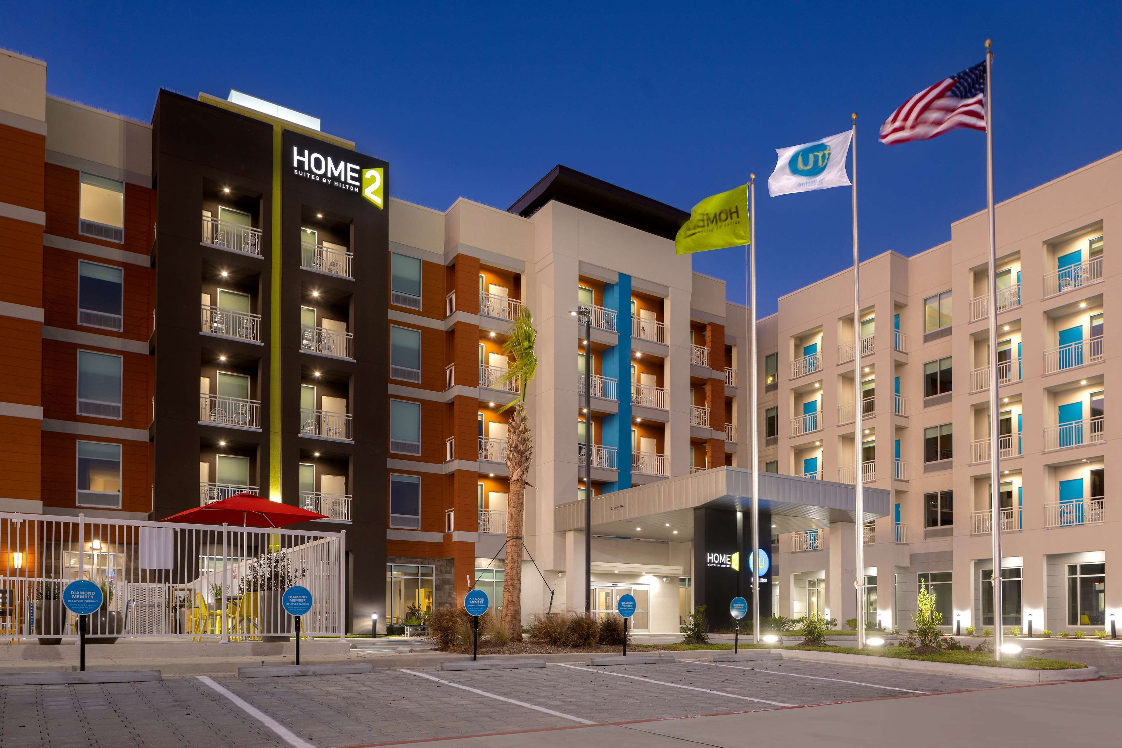 A multi-story hotel with a modern design, featuring balconies, a covered entrance, and flags.