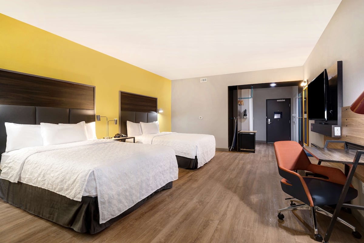 Een hotelkamer met twee bedden, een bureau, een stoel en een televisie.