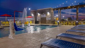 Una piscina interior con tobogán, sillas amarillas y una zona cubierta con sombrillas.