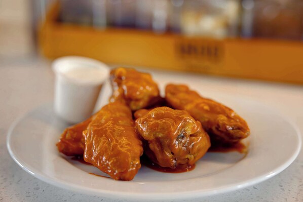 A plate of chicken wings with a side of dipping sauce.