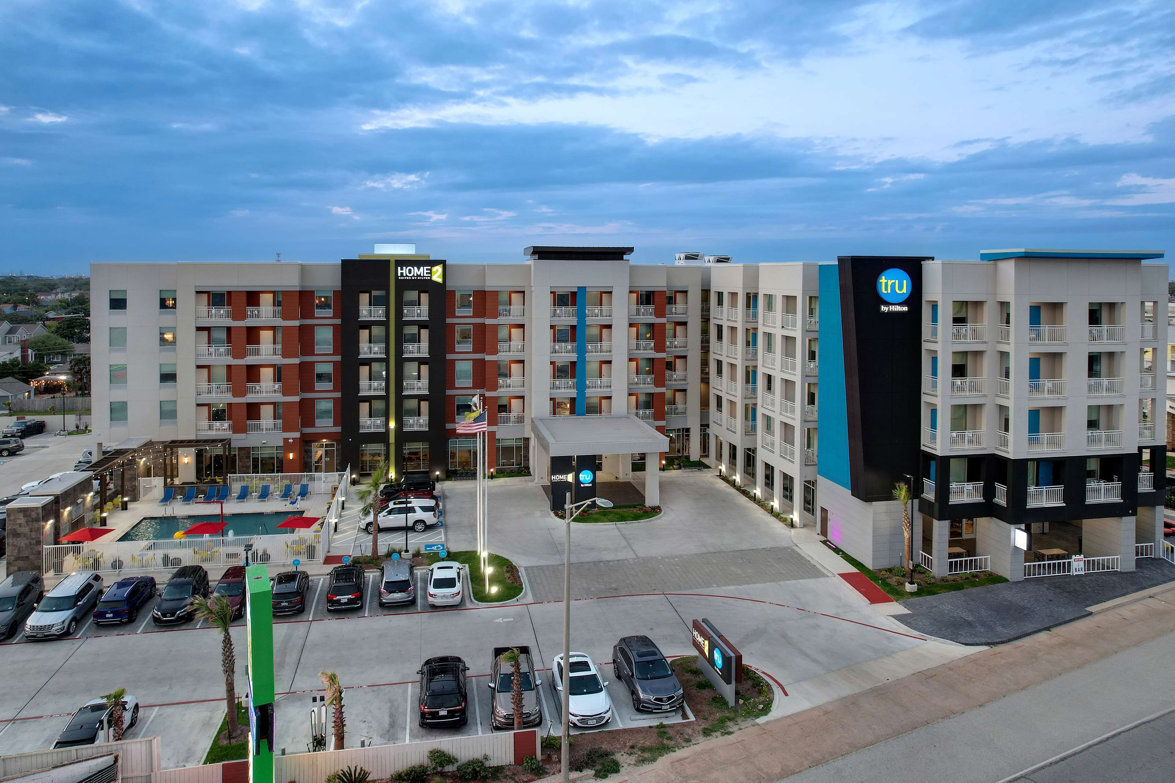 A hotel with multiple floors, a swimming pool, and a parking lot.