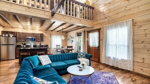 A spacious living area with a blue sectional sofa, a round coffee table, and a wooden ceiling with exposed beams. - Perfect for Girls Trips! 4 Suites & Amazing Pool! (Gatlinburg)