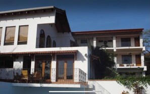 A two-story building with a balcony and a covered patio area.