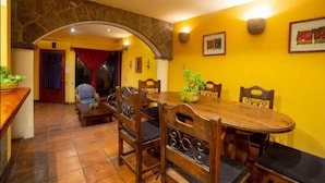 A dining area with a round wooden table and six chairs, a potted plant, and a stone archway. - Beautiful Lakefront home: gardens  (Santiago Atitlan)