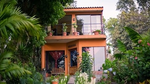 A two-story house with a balcony, surrounded by lush greenery and potted plants. - Beautiful Lakefront home: gardens  (Santiago Atitlan)