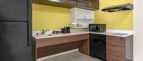 A modern kitchen with a black refrigerator, wooden cabinets, a microwave, and a dishwasher.