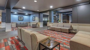 A spacious lobby with multiple seating areas, a patterned carpet, and a bar area in the background. - MainStay Suites Lexington I-75 (Lexington)