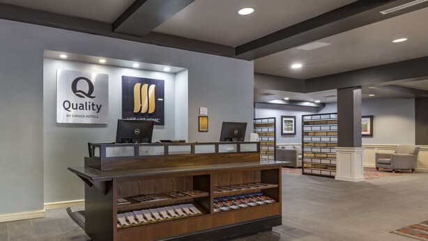 A reception desk with a wooden finish, a sign reading "Quality by Choice Hotels," and a computer monitor. - MainStay Suites Lexington I-75 (Lexington)