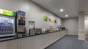 A breakfast bar with a refrigerated drink dispenser, a coffee machine, and a variety of food items. - MainStay Suites Lexington I-75 (Lexington)