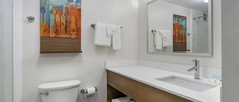 A modern bathroom with a toilet, sink, and mirror. There are two towels hanging on the wall.