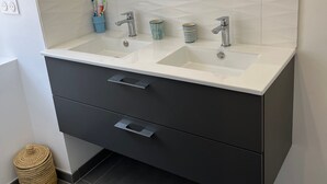 Un baño moderno con tocador de doble lavabo, un espejo grande y una toalla colgada en la pared.
