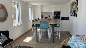 Una cocina moderna con armarios blancos, una mesa de comedor de madera y sillas azules.