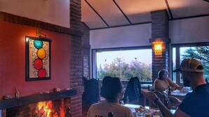 Un restaurant doté d’une cheminée, de murs en briques et de grandes fenêtres.