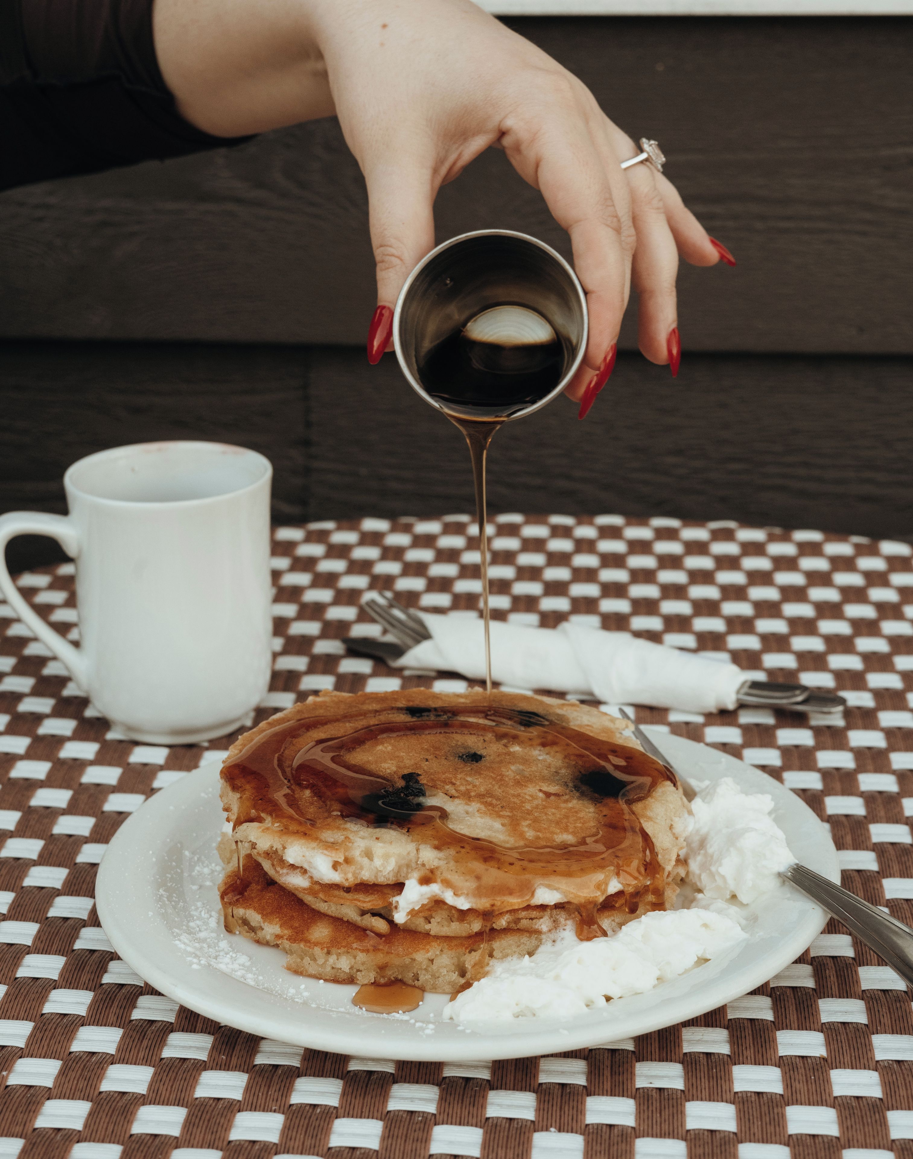 A plate of pancakes with syrup being poured onto them.